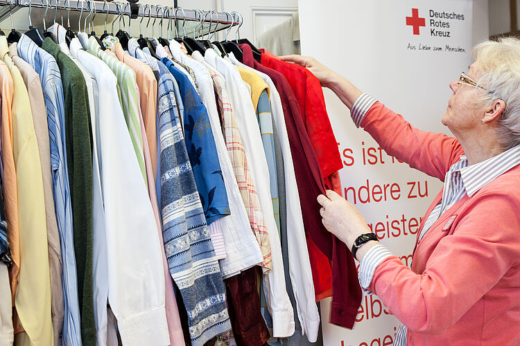 Mitarbeiterin im Kleiderladen schaut Kleidung durch.