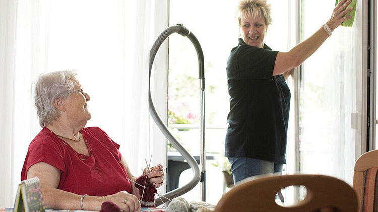 DRK-Mitarbeiterin erledigt den Hausputz bei einer pflegebedürftigen Dame.