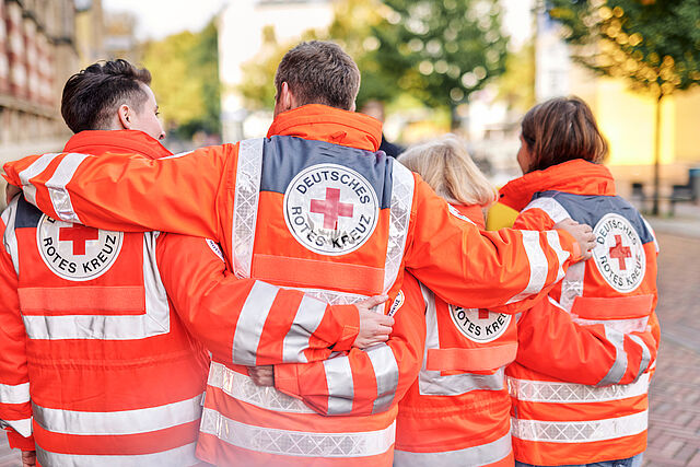 Vier DRKler mit Einsatzjacken von hinten im Arm
