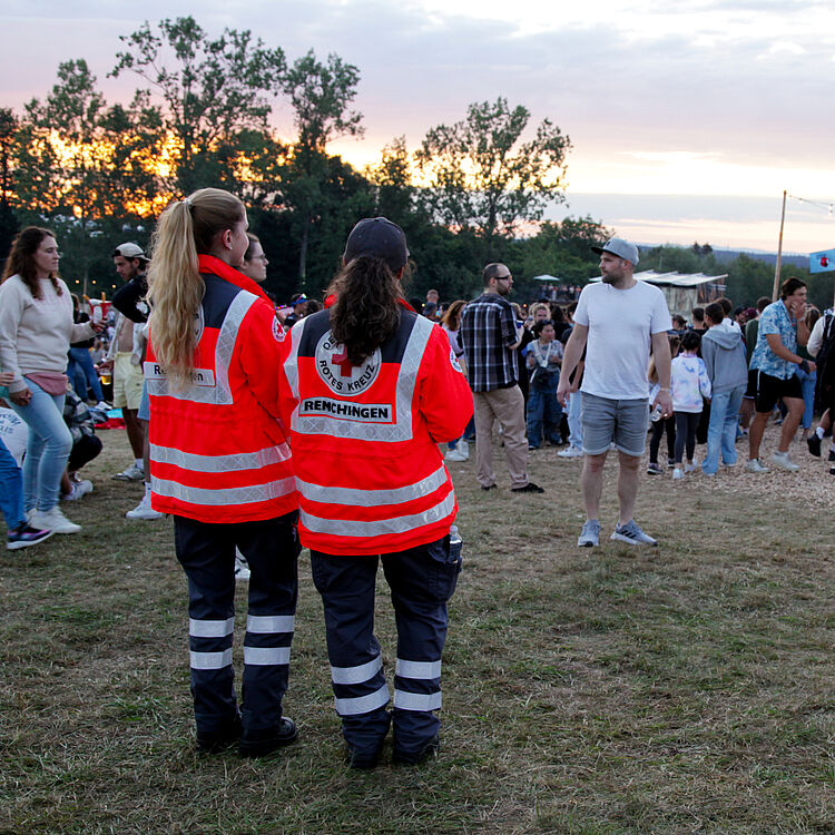 Sanitätsdienst_Happiness Zwei Sanitätshelferinnen passen auf dem Happiness-Festival auf und blicken aufs Publikum.